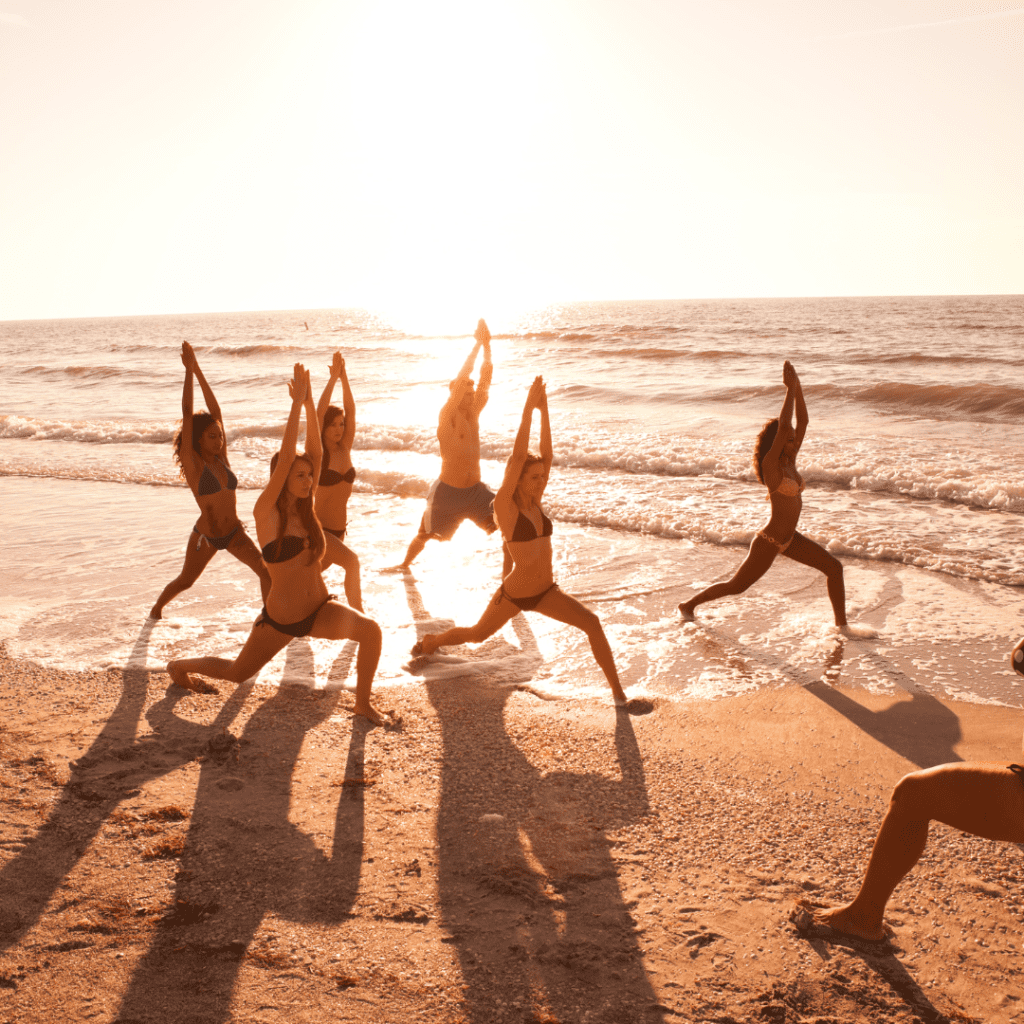 Outdoor fundraising event ideas: 6 people on the beach doing yoga at sunset