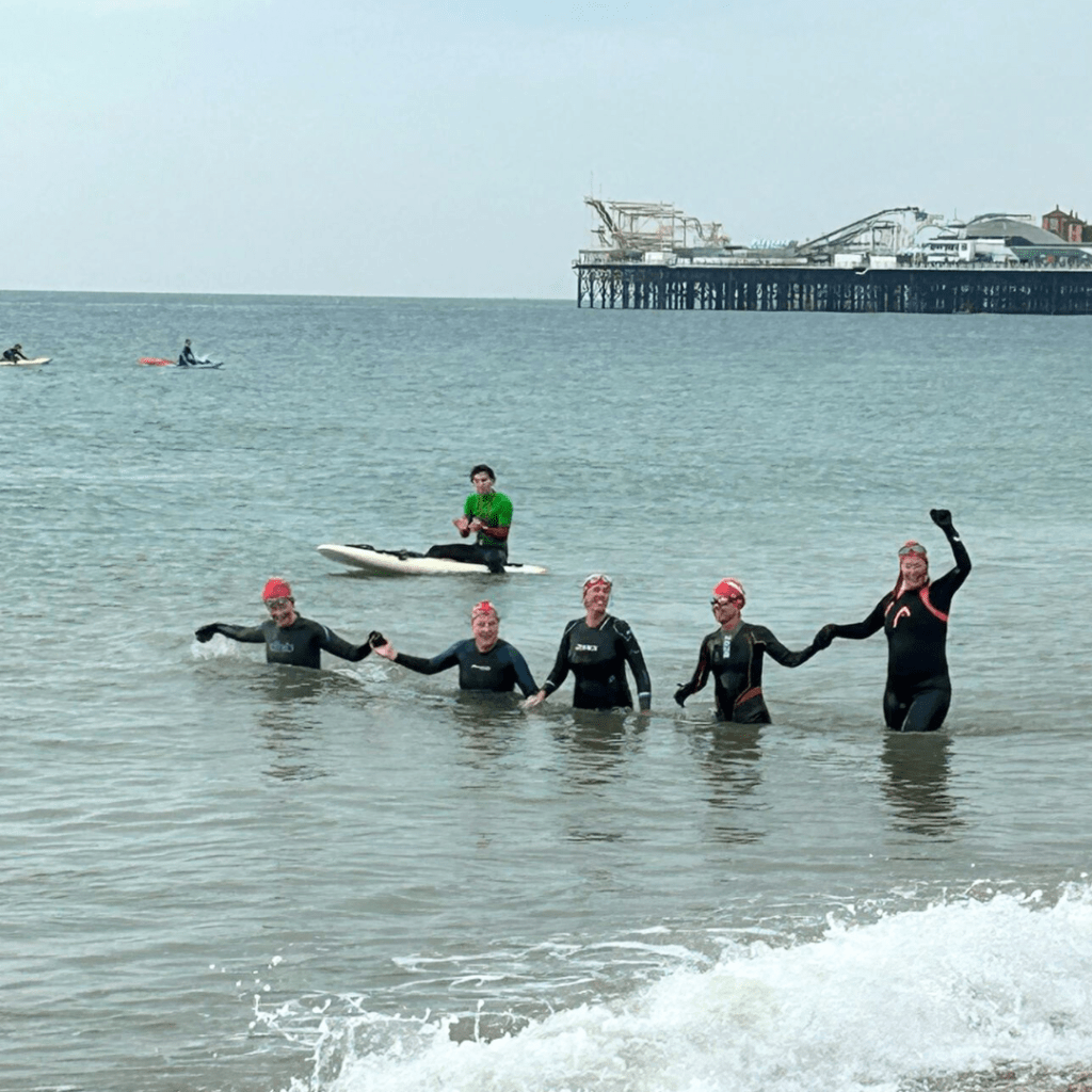 5k sea swim - 5 sea swimmers walking out of the water holding hands