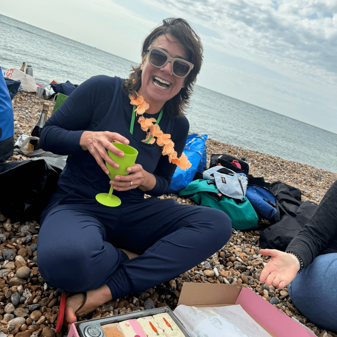 5km sea swim - women on beach holding glass with a picnic in front of her
