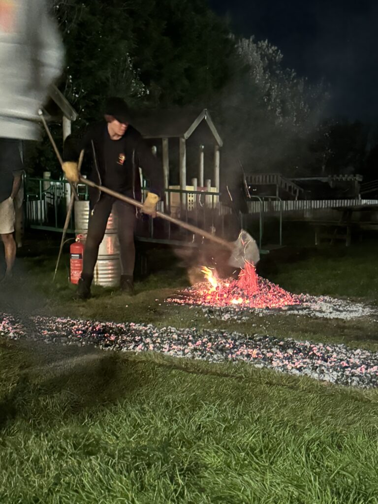 the fire tender gtting the coals ready to tip onto the firewalk area