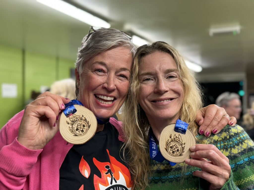 Two women holding firewalking medals