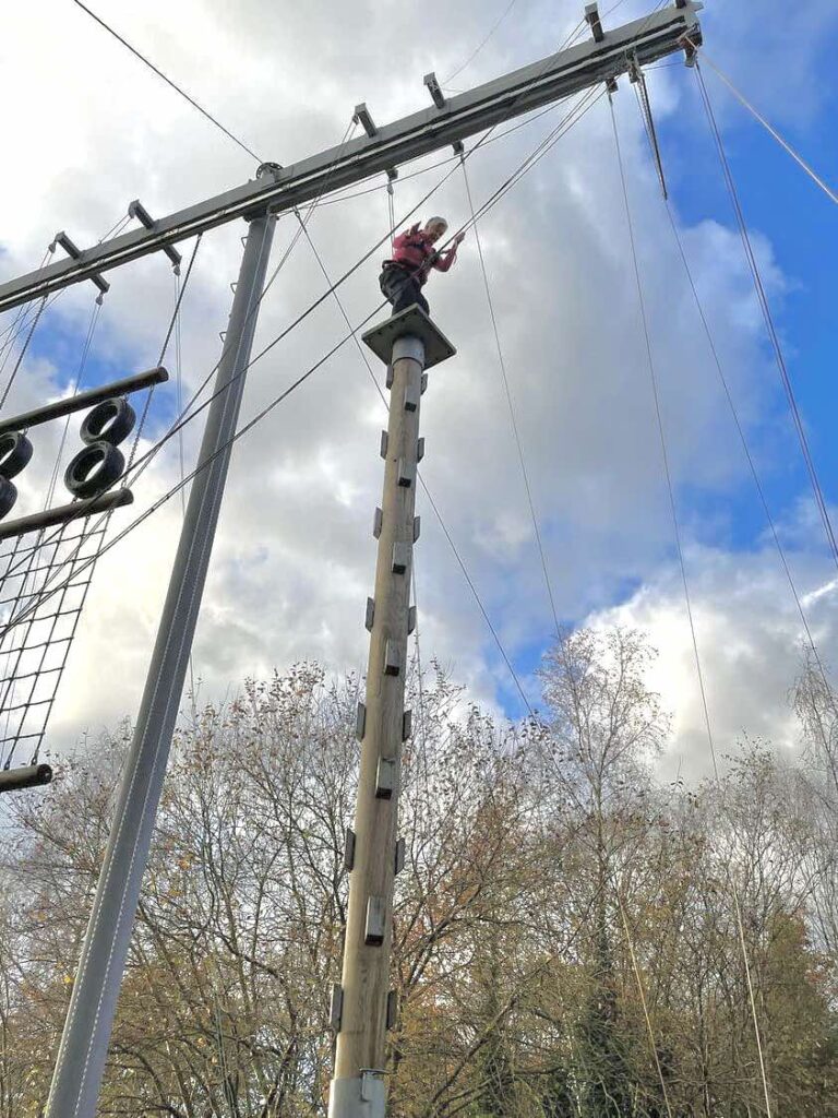 one women standing on top a 50 ft pole ready to jump off wearing a safety harness is out of your comfort zone
